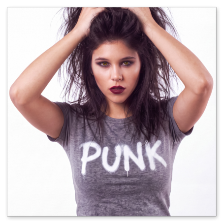 Porträt einer jungen Frau mit wild zerzaustem, dunklem Haar vor weißem Hintergrund. Sie greift sich mit beiden Händen in die Haare, trägt ein graues T-Shirt mit dem weißen Graffiti-Aufdruck "PUNK" und blickt mit dunklem Make-up direkt in die Kamera.